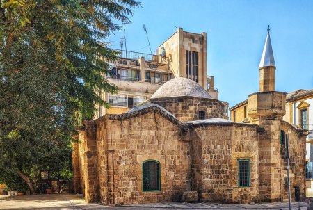 Un petit bâtiment se trouve en face d'une grande mosquée avec une haute tour à Nicosie, Chypre. Belle rue avec une architecture ancienne à Nicosie,