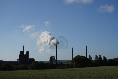 Photo for Industrial landscape with a large chimney and a cloudy sky - Royalty Free Image