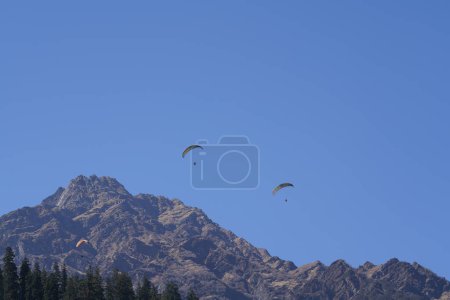 Photo for Skydivers flying over forest and mountains - Royalty Free Image