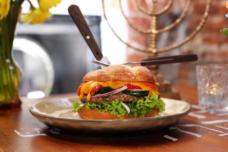Foto de Hamburguesa, hamburguesa de jalá con carne de res, cordero, verduras, salsa y bollo de jalá, en un plato, vista lateral. - Imagen libre de derechos