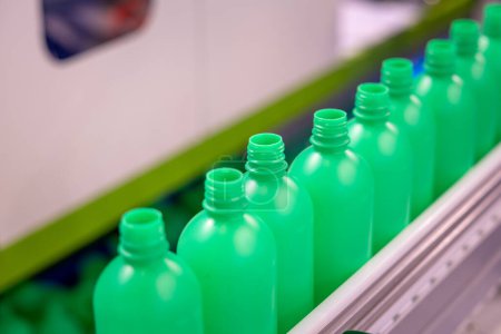 Photo for Stream of Green Plastic Bottles on Industrial Production Line. Automated Bottle Manufacturing in Progress. The Conveyor Belt of Green Bottles in a Modern Factory Setting. - Royalty Free Image