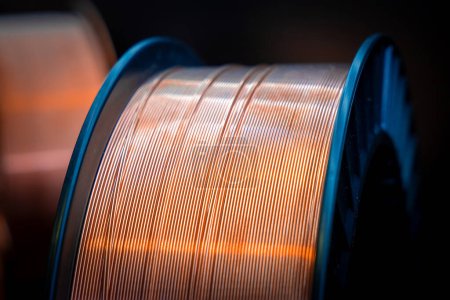 Photo for Close-up of a spool of copper wire. Shiny copper wire wound on a reel, dark background, close-up. Electronics and industrial equipment. - Royalty Free Image