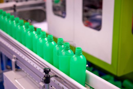 Photo for Stream of Green Plastic Bottles on Industrial Production Line. Automated Bottle Manufacturing in Progress. The Conveyor Belt of Green Bottles in a Modern Factory Setting. - Royalty Free Image