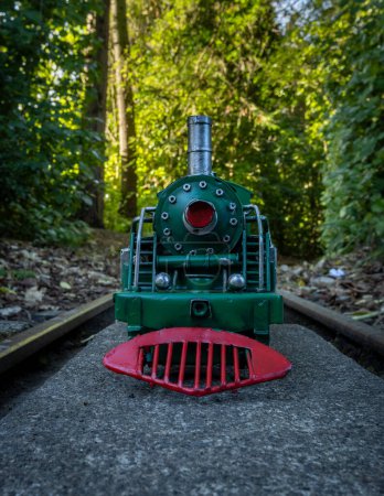 Foto de Modelo de locomotora de vapor verde con ruedas rojas con fondo de arbusto. - Imagen libre de derechos