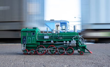 Foto de Modelo de locomotora de vapor verde con ruedas rojas con un movimiento de tren en el fondo. - Imagen libre de derechos