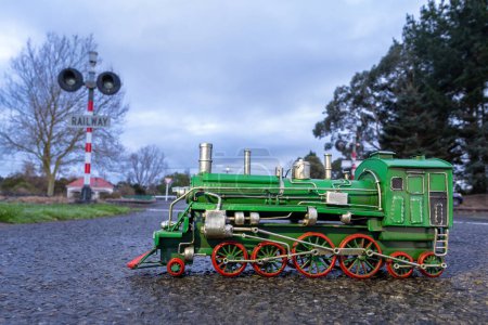 Foto de Locomotora de vapor verde con ruedas rojas en un cruce de vías férreas.. - Imagen libre de derechos