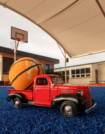 Foto de Pequeño camión rojo con una bola de canasta naranja en la parte posterior. - Imagen libre de derechos