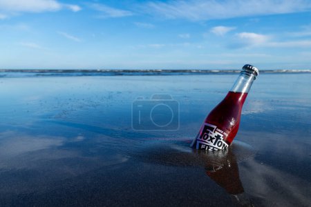 Foto de Foxton Beach, Nueva Zelanda, 4.9.2023. Una botella de vidrio de Foxton Fizz en la arena mojada de Foxton Beach. - Imagen libre de derechos