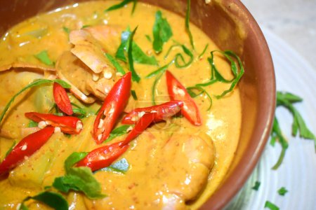 Téléchargez les photos : Gros plan sur le curry Panang ou King Creawns Red Curry assaisonnement avec tranches de chili rouge et feuilles de citron vert kaffir sur le dessus, Cuisine maison style thaï. - en image libre de droit