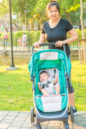 Foto de Asiática mamá usando cochecito con niño niño en parque - Imagen libre de derechos