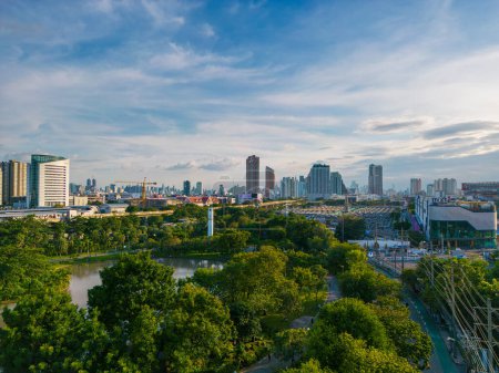 Green tree forest public park with city office building downtown of Bangkok Thailand