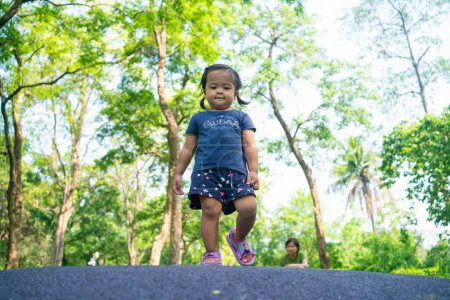 Photo for Portrait of happy asian toddler girl walking in city public tree park outdoor activity - Royalty Free Image