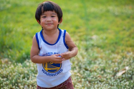 Téléchargez les photos : Portrait de heureux sourire asiatique garçon riant vert parc en plein air avec fond de jardin vert flou, jeu d'enfant en été. - en image libre de droit