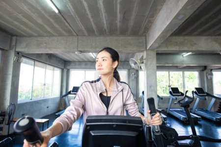 Foto de Deportiva asiática mujer haciendo ejercicio en elíptica máquina en gimnasio, cardio ejercicio - Imagen libre de derechos