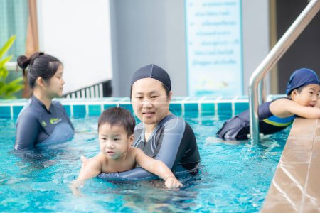 Téléchargez les photos : Adorable petit garçon nageant avec maman dans la piscine en copropriété - en image libre de droit