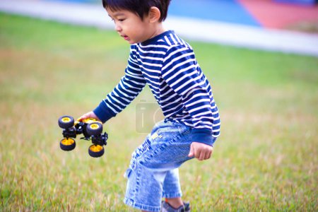 Foto de Adorable niño jugando con coche de juguete al aire libre - Imagen libre de derechos