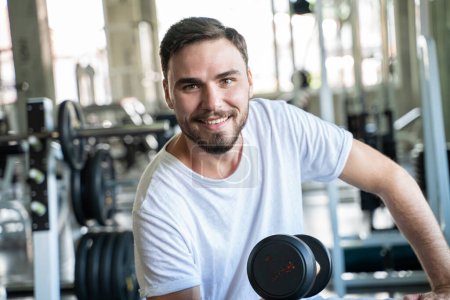 Téléchargez les photos : Bel homme athlétique exercice avec Dumnbell dans la salle de gym. Mode de vie sain - en image libre de droit