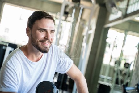 Photo for Handsome Athletic Man Exercising With Dumnbell in Gym. Healthy Lifestyle - Royalty Free Image