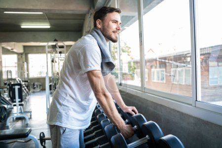 Téléchargez les photos : Bel homme athlétique exercice avec Dumnbell dans la salle de gym. Mode de vie sain - en image libre de droit