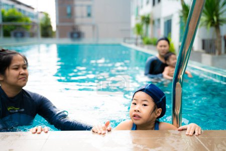 Téléchargez les photos : Adorable petit garçon nageant avec maman dans la piscine en copropriété - en image libre de droit