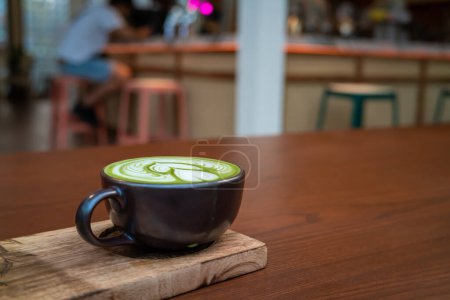 Foto de Arte latte matcha caliente en la mesa de madera, bebida de aroma japonés en la cafetería - Imagen libre de derechos