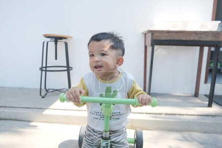 Téléchargez les photos : Joyeux tout-petit garçon vélo d'équilibre d'équitation dans la ville - en image libre de droit
