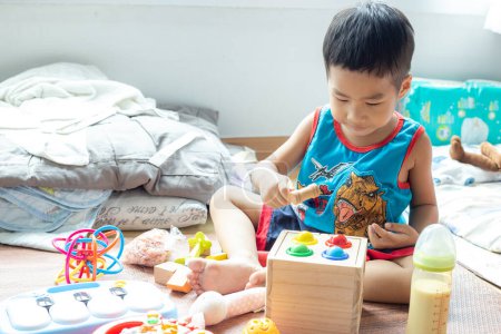 Téléchargez les photos : Joyeux petit garçon jouant avec des jouets en bois - en image libre de droit