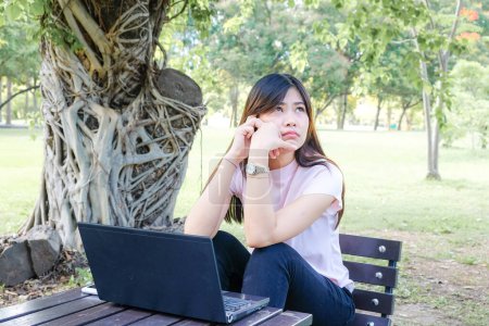 Téléchargez les photos : Workimg femme d'affaires avec smartphone et ordinateur portable dans le parc - en image libre de droit