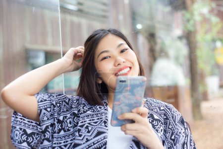 Téléchargez les photos : Femme asiatique en utilisant smartphone dans le café - en image libre de droit