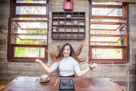 Téléchargez les photos : Jolie femme utilisant tablette assise à la table en bois dans le café, style de vie libre - en image libre de droit
