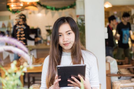 Téléchargez les photos : Belle jeune femme d'affaires assise au restaurant en utilisant une tablette numérique pc pour la communication - en image libre de droit