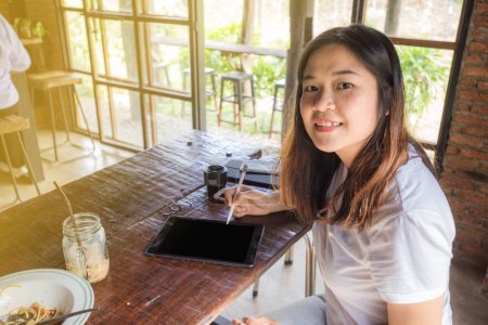 Téléchargez les photos : Femme utilisant la tablette pc avec stylo électronique dans le café - en image libre de droit