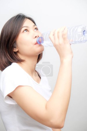 Foto de Joven asiático mujer beber agua de botella aislado en blanco fondo - Imagen libre de derechos