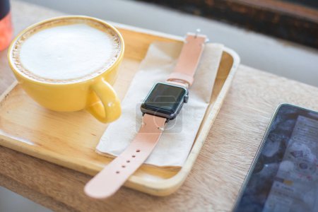 Foto de Reloj inteligente con correa de cuero genuino y café en la cafetería - Imagen libre de derechos