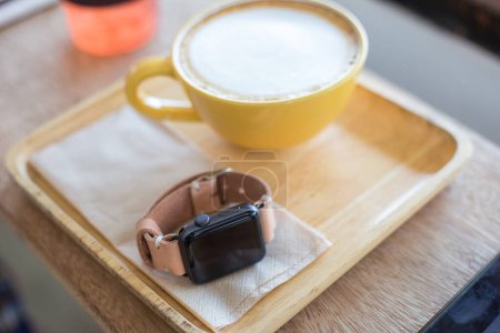 Foto de Reloj inteligente con correa de cuero genuino y café en la cafetería - Imagen libre de derechos
