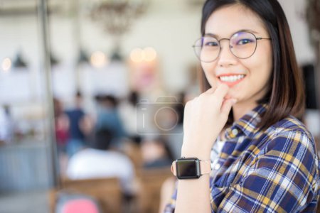 Photo for Asian woman wearing smart watch in coffee shop, blurred view of people background - Royalty Free Image