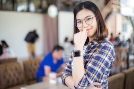 Téléchargez les photos : Femme asiatique portant montre intelligente dans le café, vue floue des gens de fond - en image libre de droit
