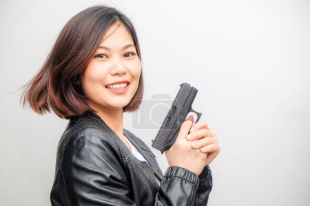 Téléchargez les photos : Belle asiatique femme détective tenant pistolet posant sur fond blanc - en image libre de droit