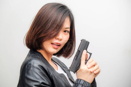 Photo for Beautiful asian female detective holding gun posing against white background - Royalty Free Image