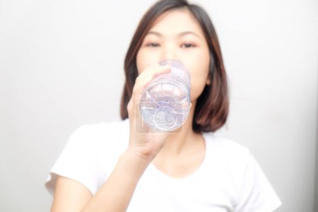 Foto de Joven asiático mujer beber agua de botella aislado en blanco fondo - Imagen libre de derechos