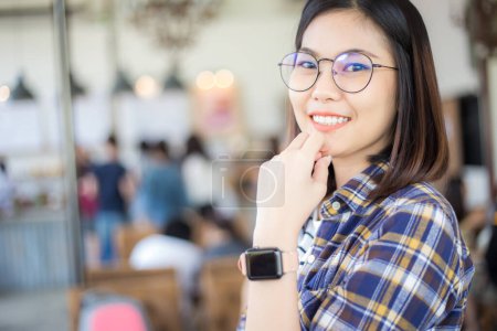 Téléchargez les photos : Femme asiatique portant montre intelligente dans le café, vue floue des gens de fond - en image libre de droit