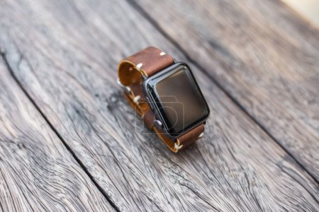 Photo for Smart watch leather strap on wooden table - Royalty Free Image