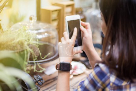 Téléchargez les photos : Femme d'affaires avec montre intelligente et téléphone boire du café chaud dans un café vintage - en image libre de droit