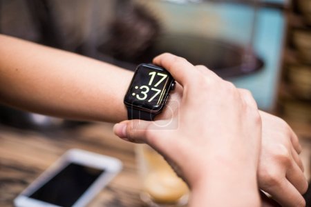 Woman using smart watch in cafe, close up on hand