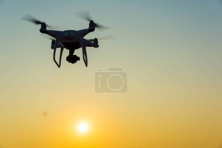 Foto de Silueta de quadcopter volando sobre la ciudad al atardecer - Imagen libre de derechos