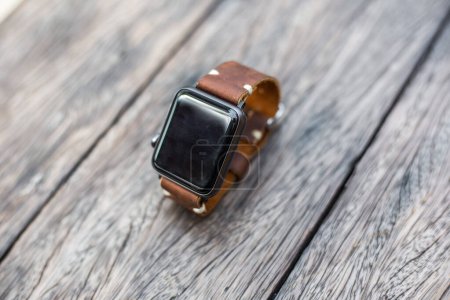 Foto de Reloj inteligente con correa de reloj de cuero genuino en mesa de madera - Imagen libre de derechos