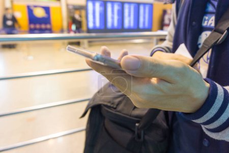 Foto de Mano del hombre utilizando el teléfono inteligente en el aeropuerto, vacaciones y concepto de viaje - Imagen libre de derechos