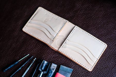 Foto de Billetera bifold de cuero genuino y herramientas para trabajar con cuero, objetos artesanales - Imagen libre de derechos