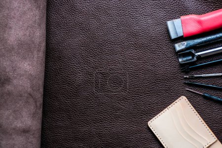 Téléchargez les photos : Portefeuille bifold en cuir véritable travaillant avec un outil sur un objet artisanal en cuir - en image libre de droit