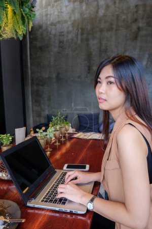 Photo for Beautiful Asian business woman working with laptop sitting in coffee shop - Royalty Free Image
